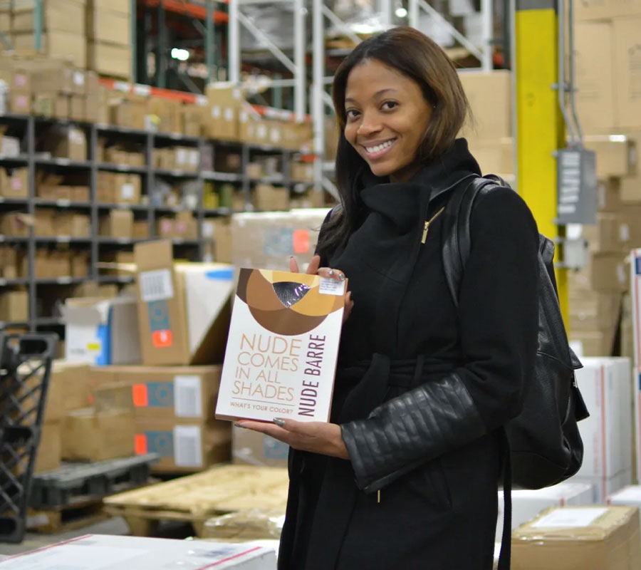 Erin at a factory with product packaging